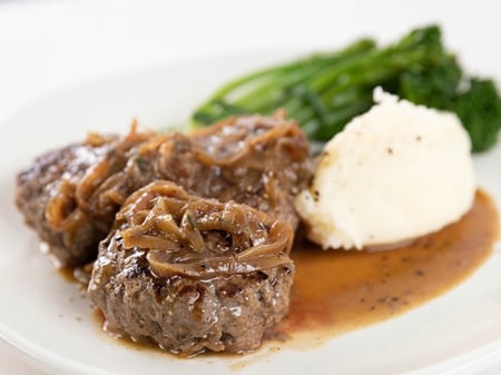 Braised Rissoles in an onion and bacon gravy with mashed potato and greens.